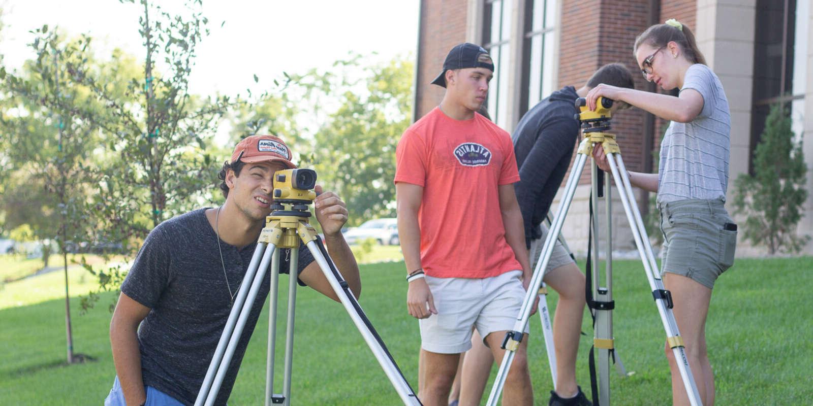 Several students looking through tripod cameras